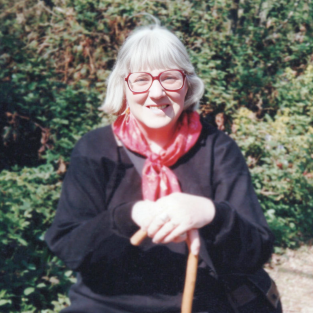 Doreen-outside-wearing-red-neck-scarf-and-holding-a-walking-stick